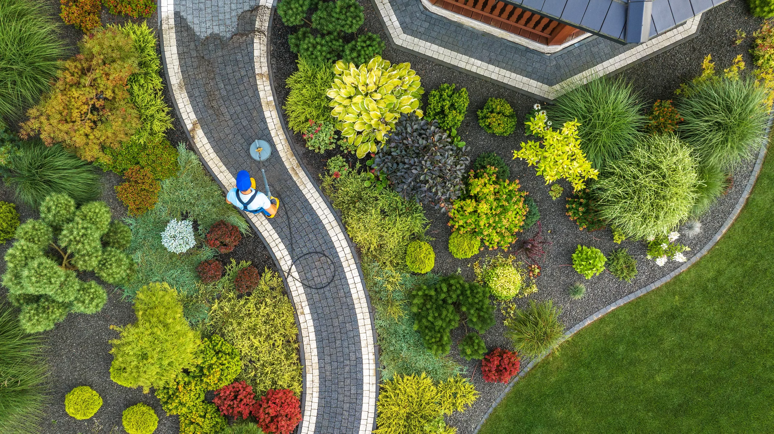 An aerial view of a service crew cleaning the pathway of the landscape of the house.